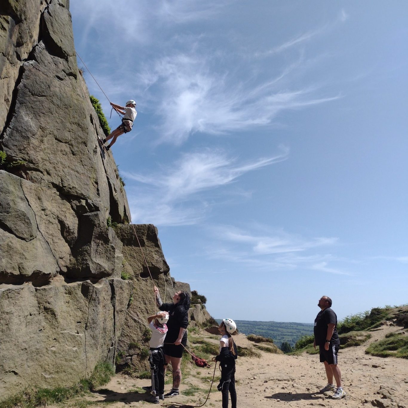 A young person scaling a climbing wall with safety gear during a rock climbing session.