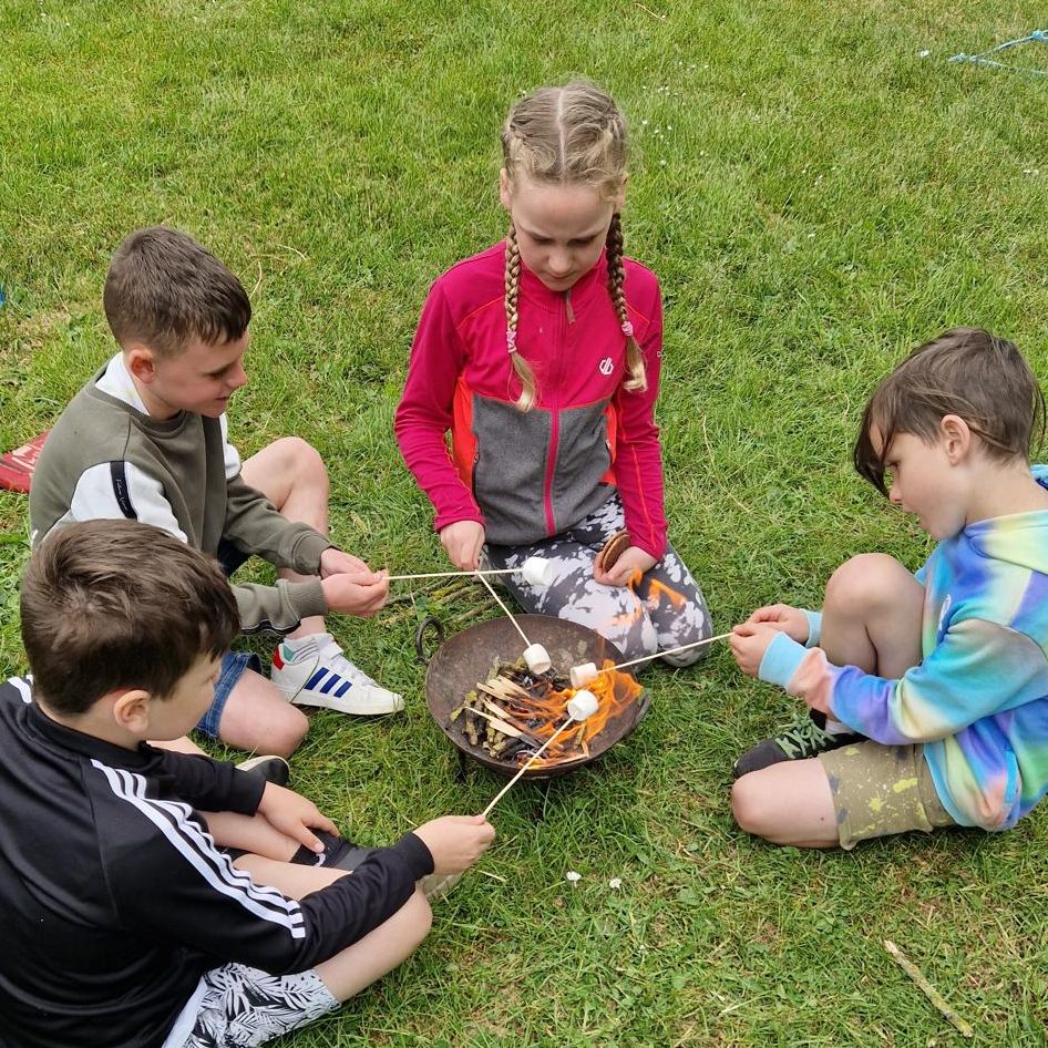 Young people learning bushcraft skills and building small campfires outdoors.